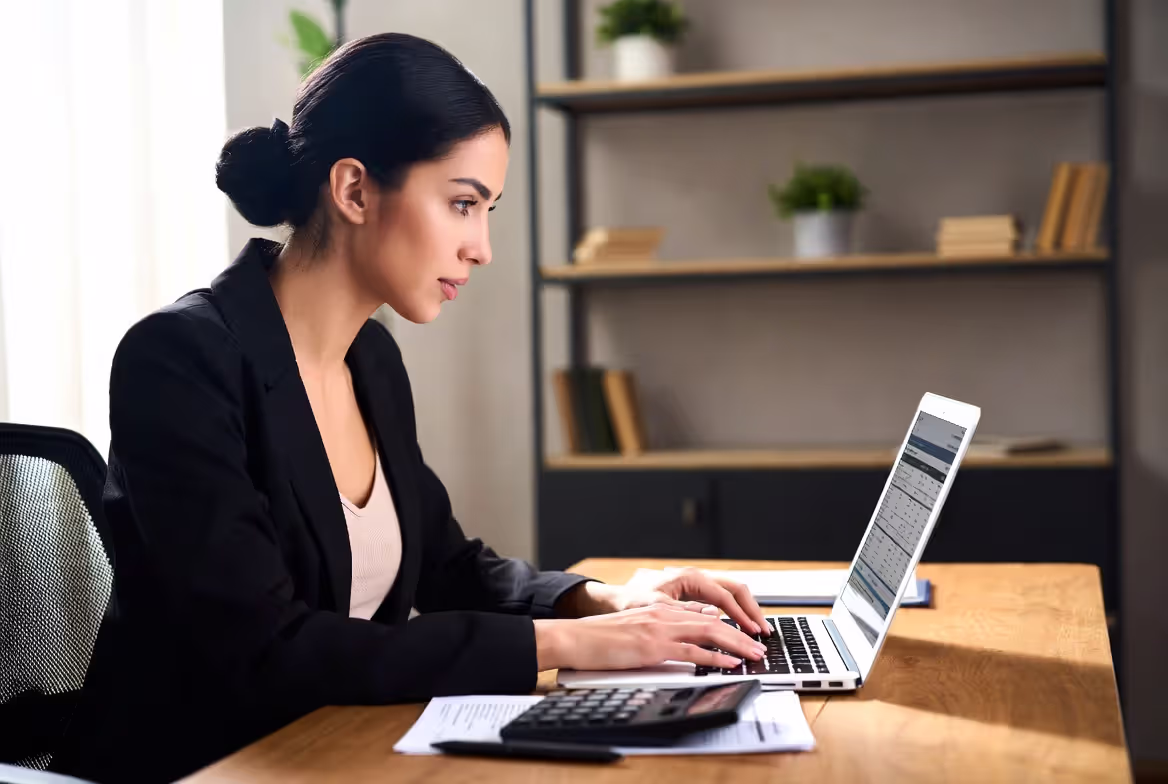 Person checking tax refund status online with tax documents nearby